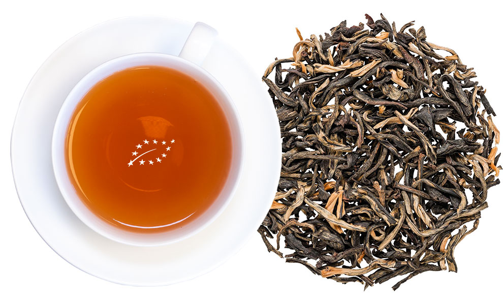 Weiße Tasse mit schwarzem Tee und losen Teeblättern