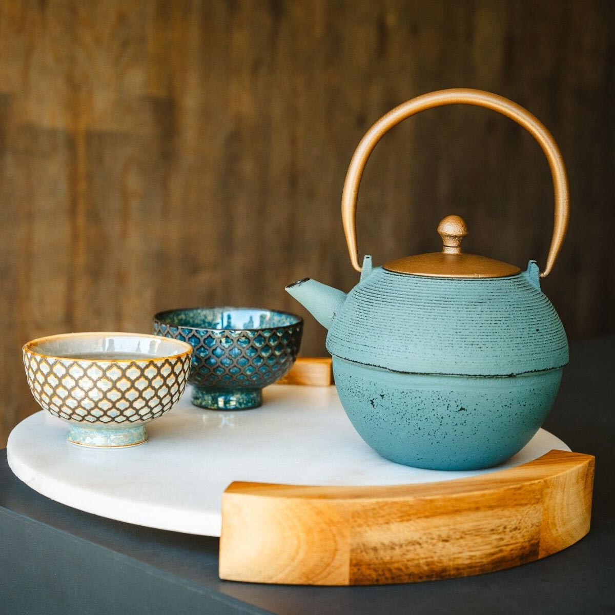 Blue-green Japanese teapot with two patterned cups on tray