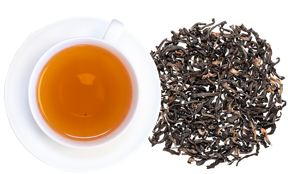 Weiße Tasse mit schwarzem Tee und losem Blatttee