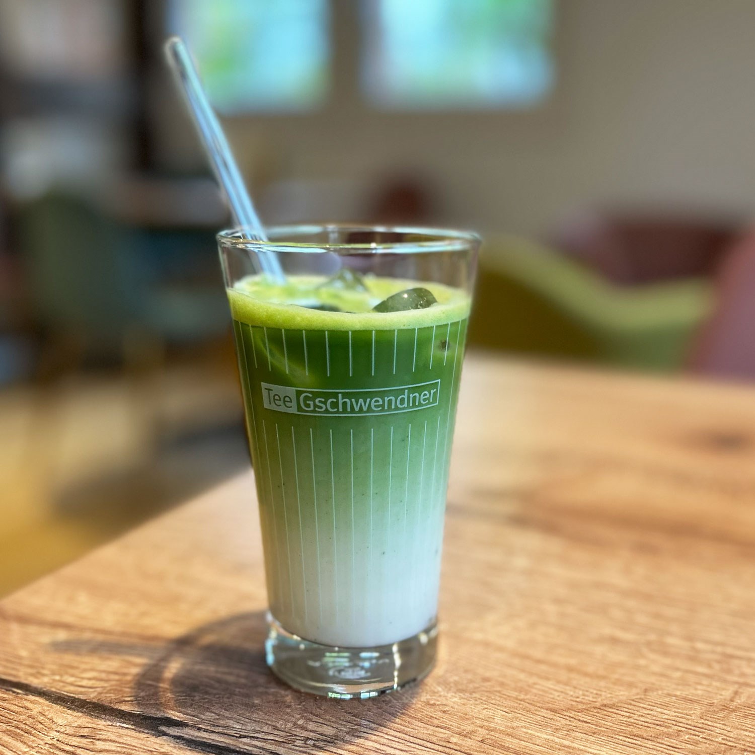 Eiskalter grüner Tee Latte im Glas mit Strohhalm