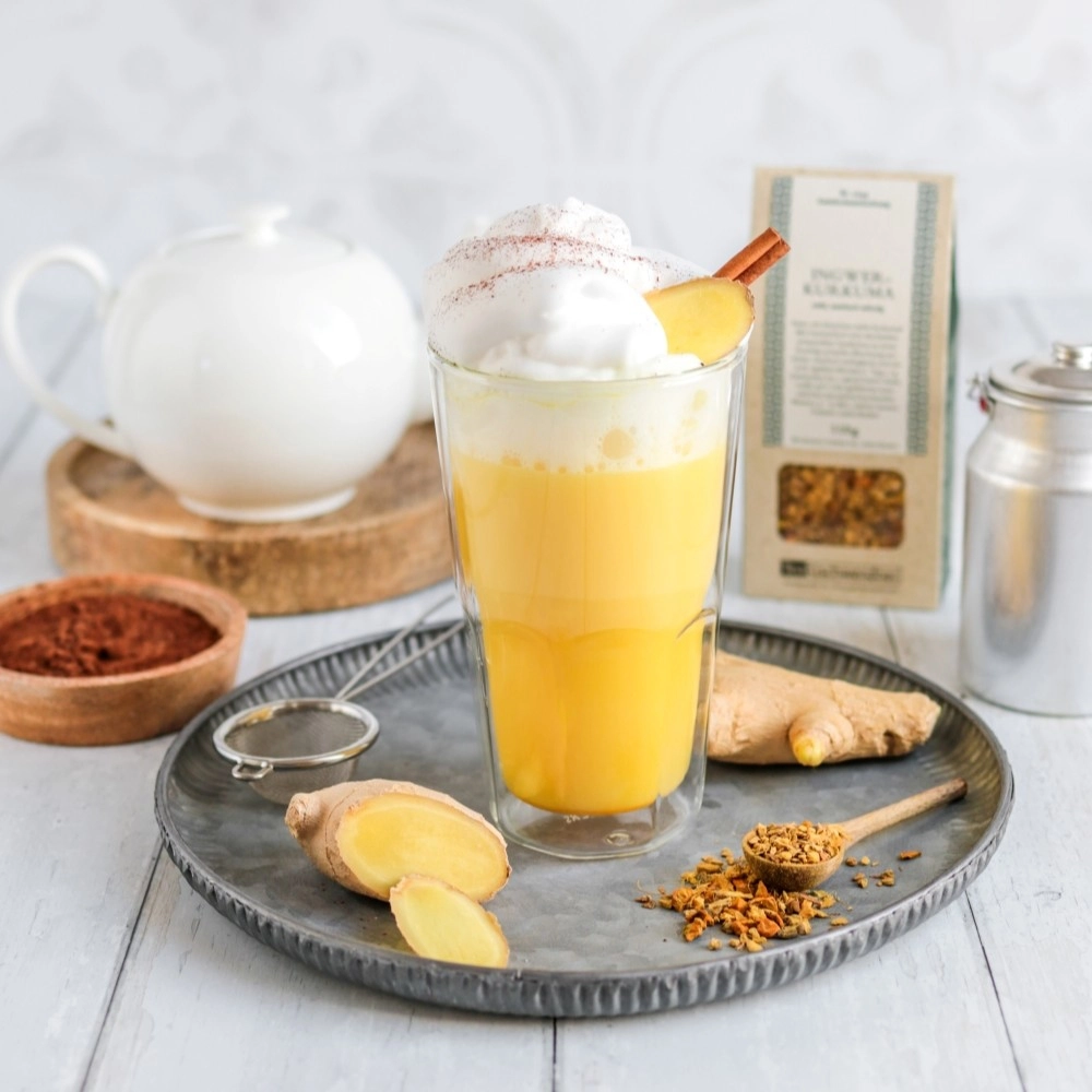 Glas Goldene Milch mit Ingwerstücken und Gewürzen