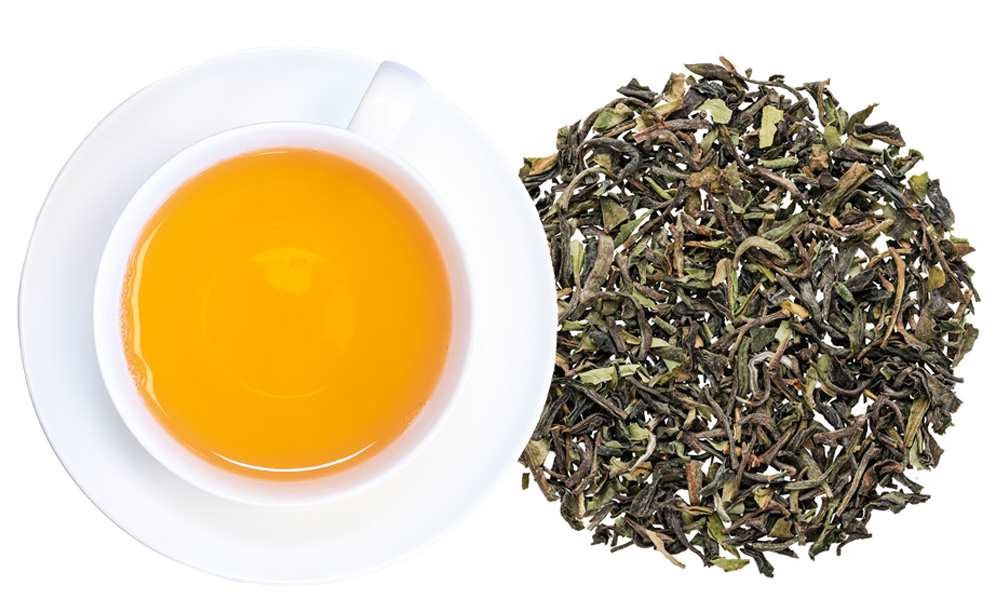 Weiße Tasse Darjeeling-Tee neben losen Blättern, tee, tee-blätter, honiggelb, grüntee?, tee-blätter