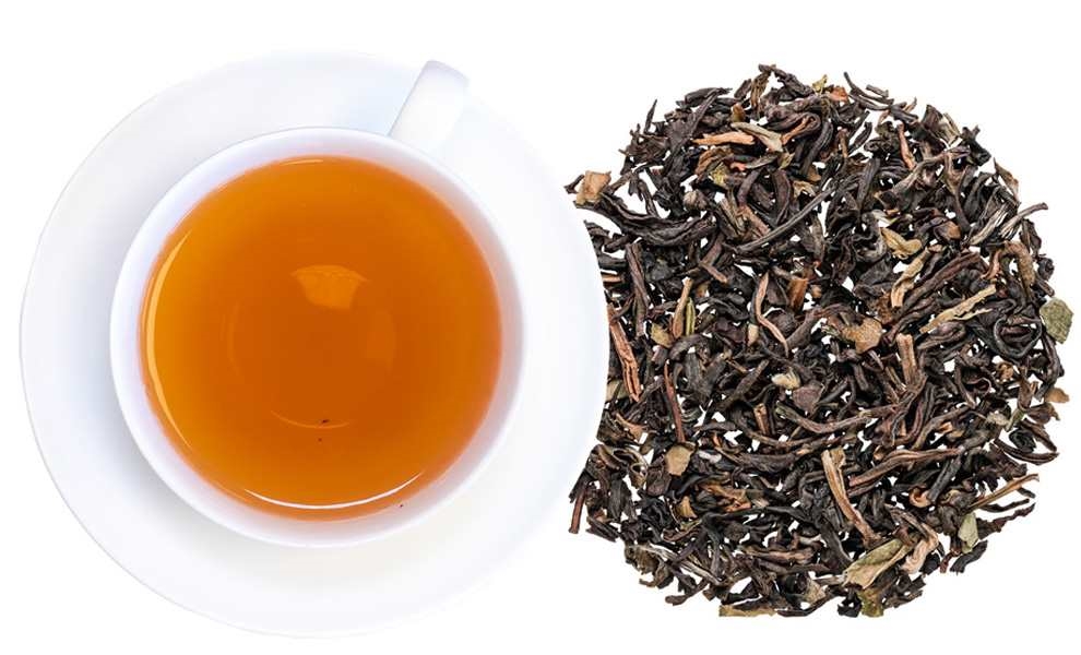 Weiße Tasse Schwarztee neben losen Teeblättern, tee, schwarzer tee, lose blätter, orange farbe, tasse