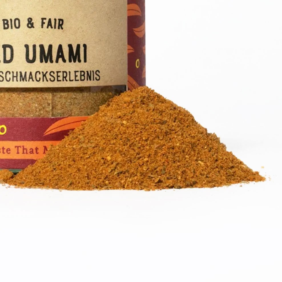 Heap of organic Bold Umami spice blend in front of the decorative spice jar