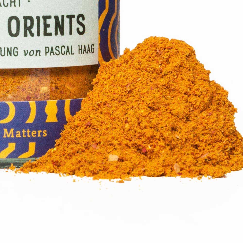 Close-up of orange oriental spice blend next to its spice jar
