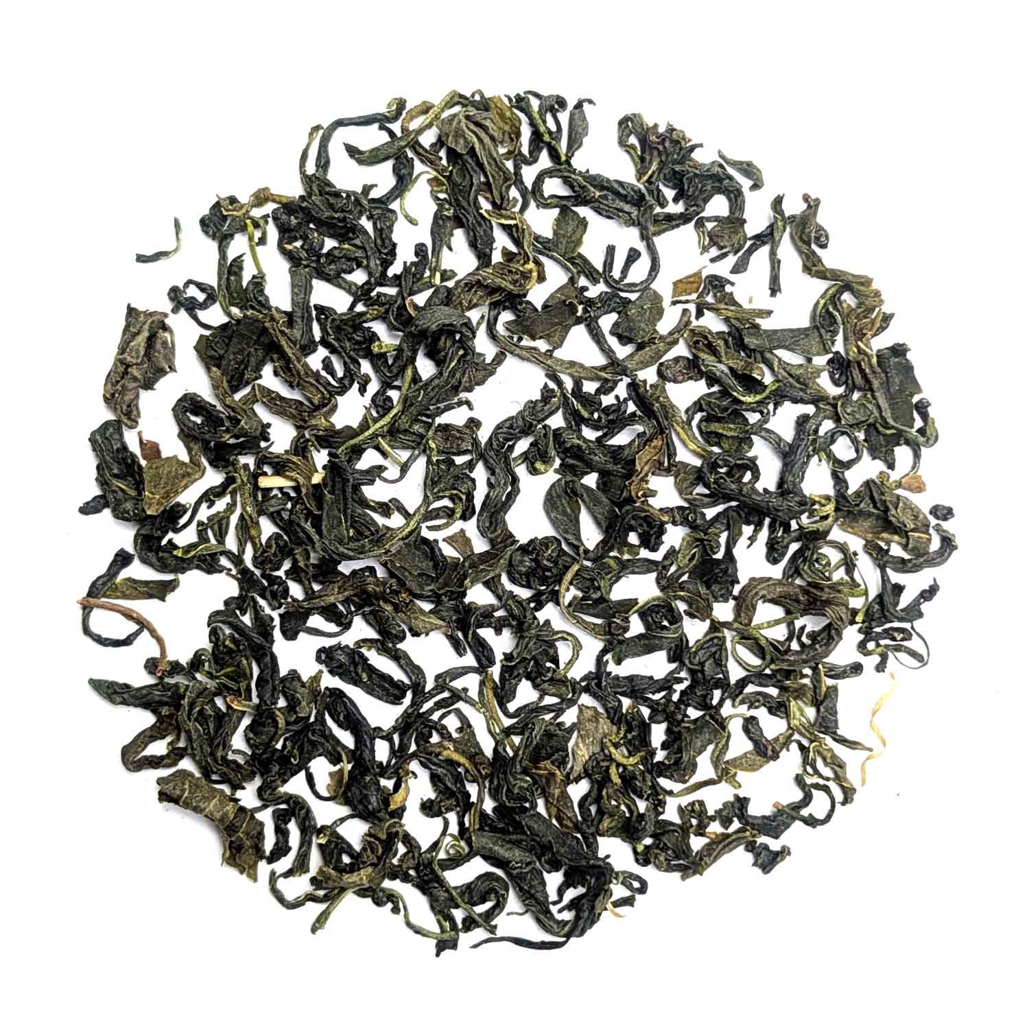 Close-up of loose green tea made from whole, twisted tea leaves on a white background