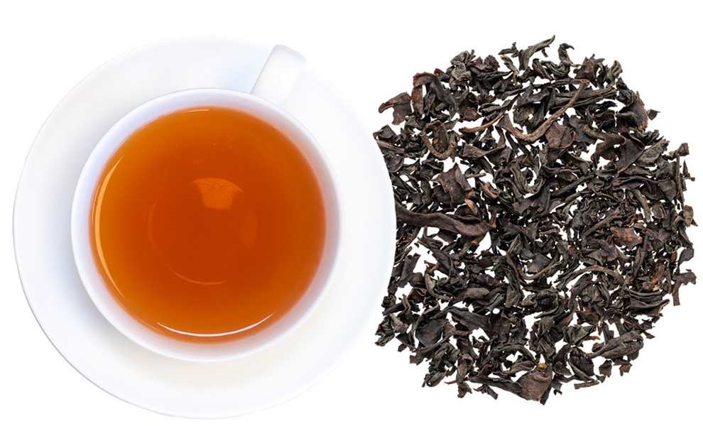 Tasse schwarzer Tee mit losen Teeblättern daneben, tee, schwarzer tee, lose tee-blätter, teetasse, aufbrühen