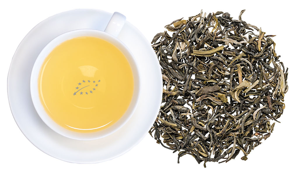 Weiße Tasse grüner Tee neben losem Blatttee