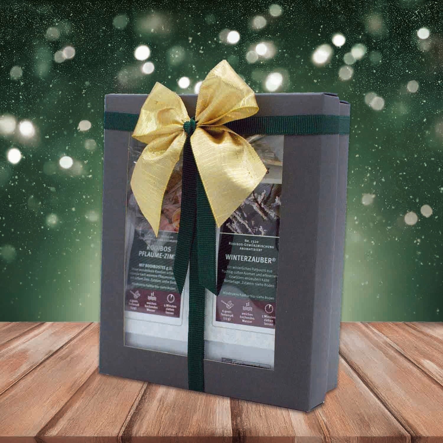 Elegant gift box with winter tea and golden bow, against a sparkling background