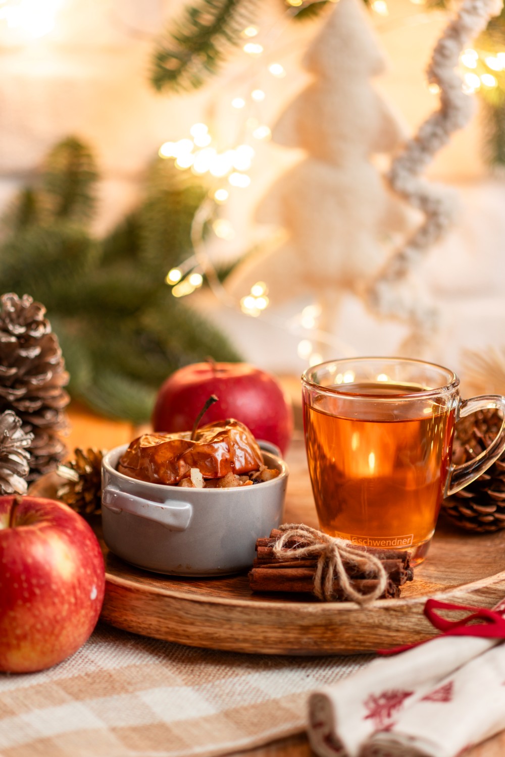 Baked apple with cup of tea and cinnamon sticks on wooden tr