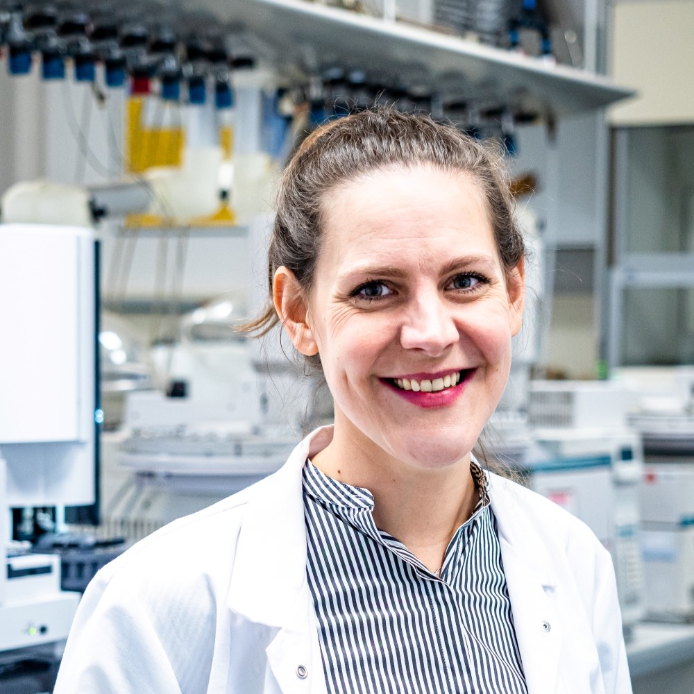Lächelnde Wissenschaftlerin im Labor mit weißem Kittel