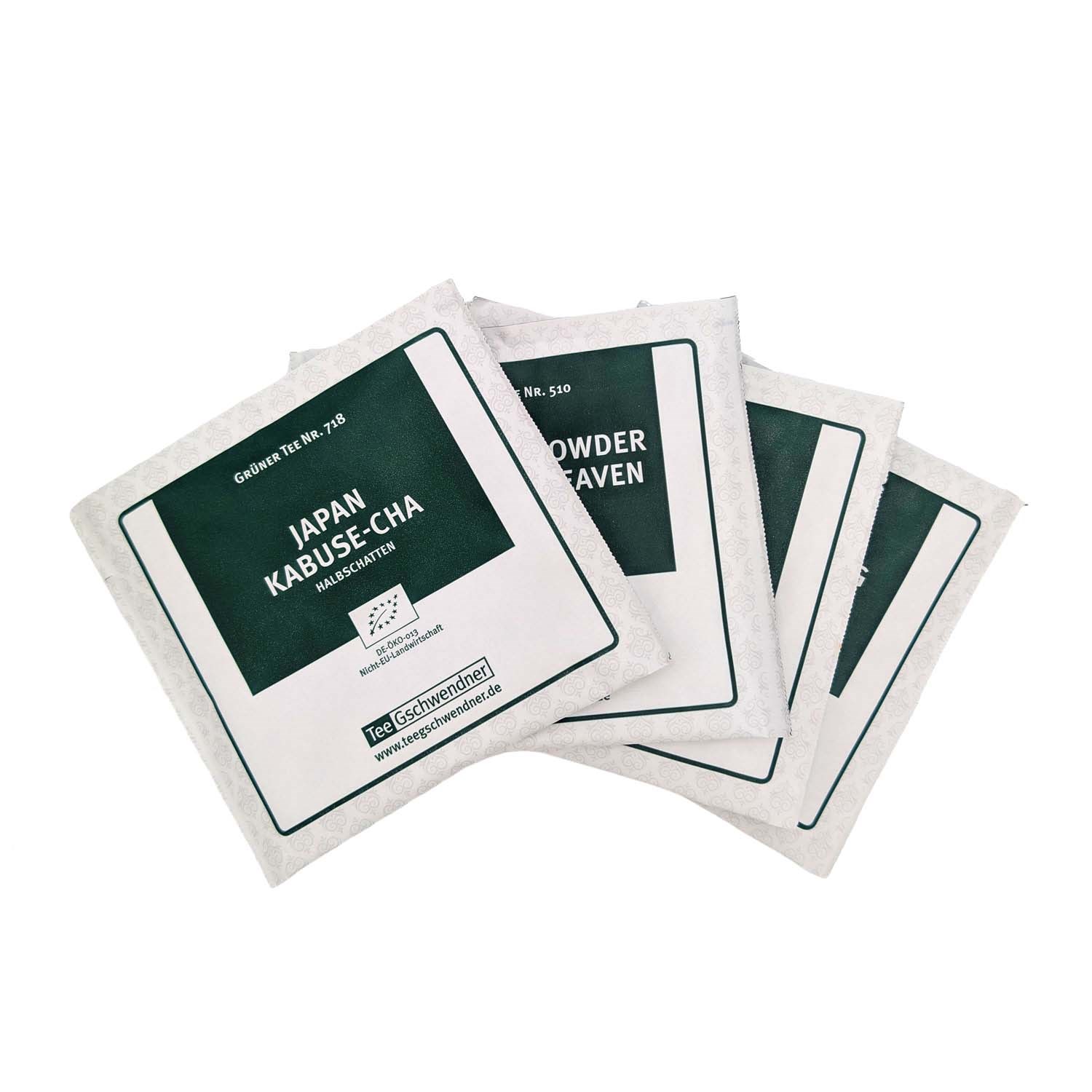 Several individually wrapped tea bags from TeeGschwendner, front pack showing green tea Japan Kabuse-cha in a white and green foil sachet