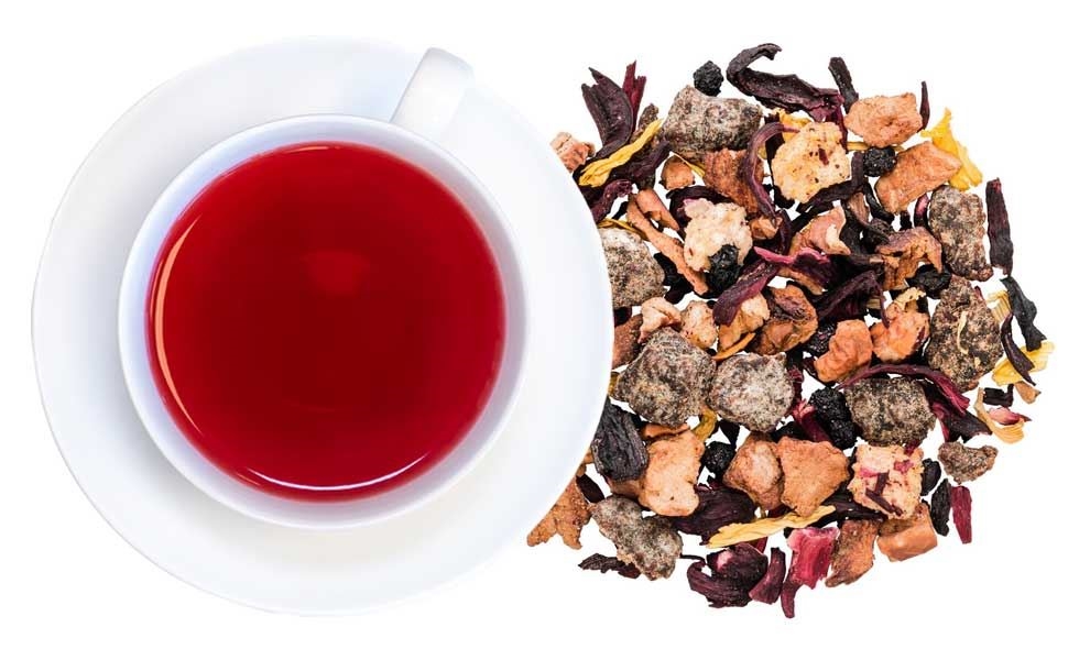 Weiße Tasse mit rotem Früchtetee und Teemischung daneben, tee, teegetränk, roter tee, kräutertee, früchtetee
