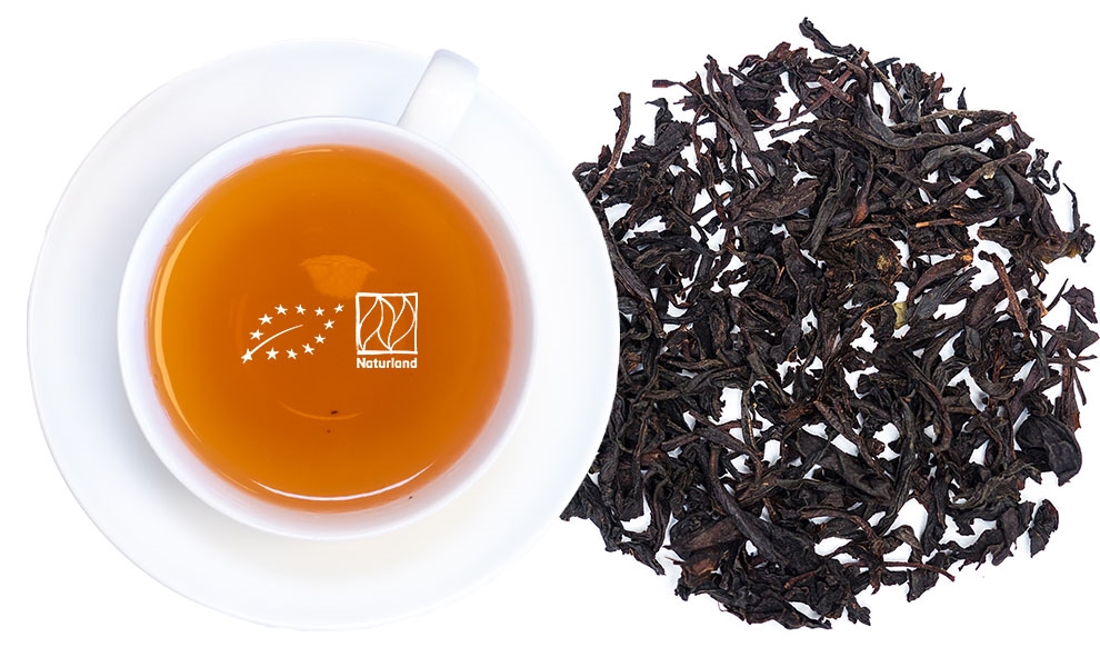 Weiße Tasse mit schwarzem Tee und losen Teeblättern, Tee, Schwarztee, Blatttee, Karamellfarbener Tee, Gewürzfrei