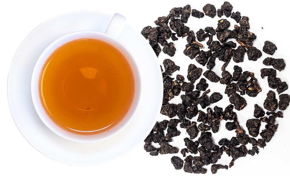 Weiße Tasse Oolong-Tee mit losen Blättern daneben, tee, teegetränk, blätter, schwarztee, cup
