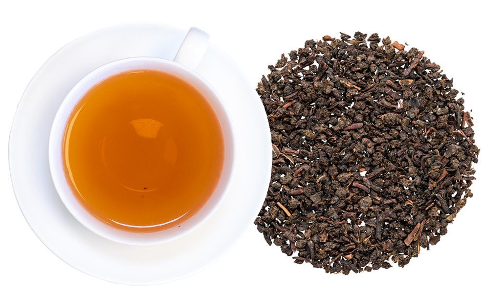 Weiße Tasse mit Schwarzem Tee und losen Teeblättern