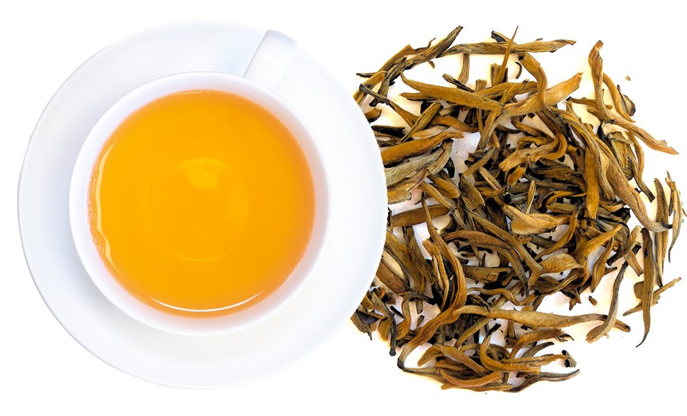 Cup of golden black tea with loose tea leaves