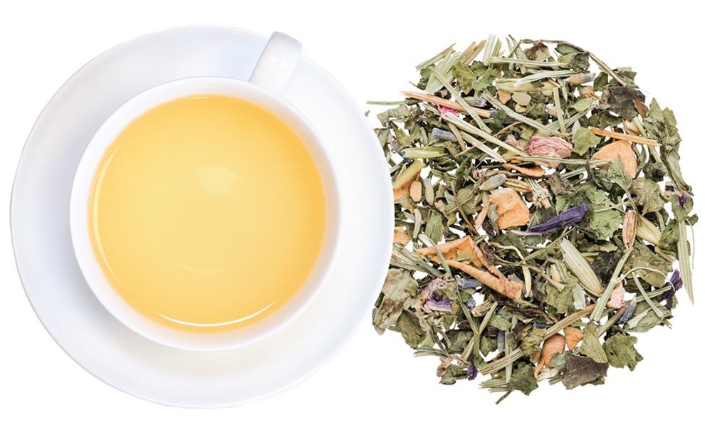 Weiße Tasse Kräutertee neben losem Kräutertee-Mix, Kräutertee, Trockenblätter, Teeblätter, Koffeinfreier Tee, Aromatischer Tee
