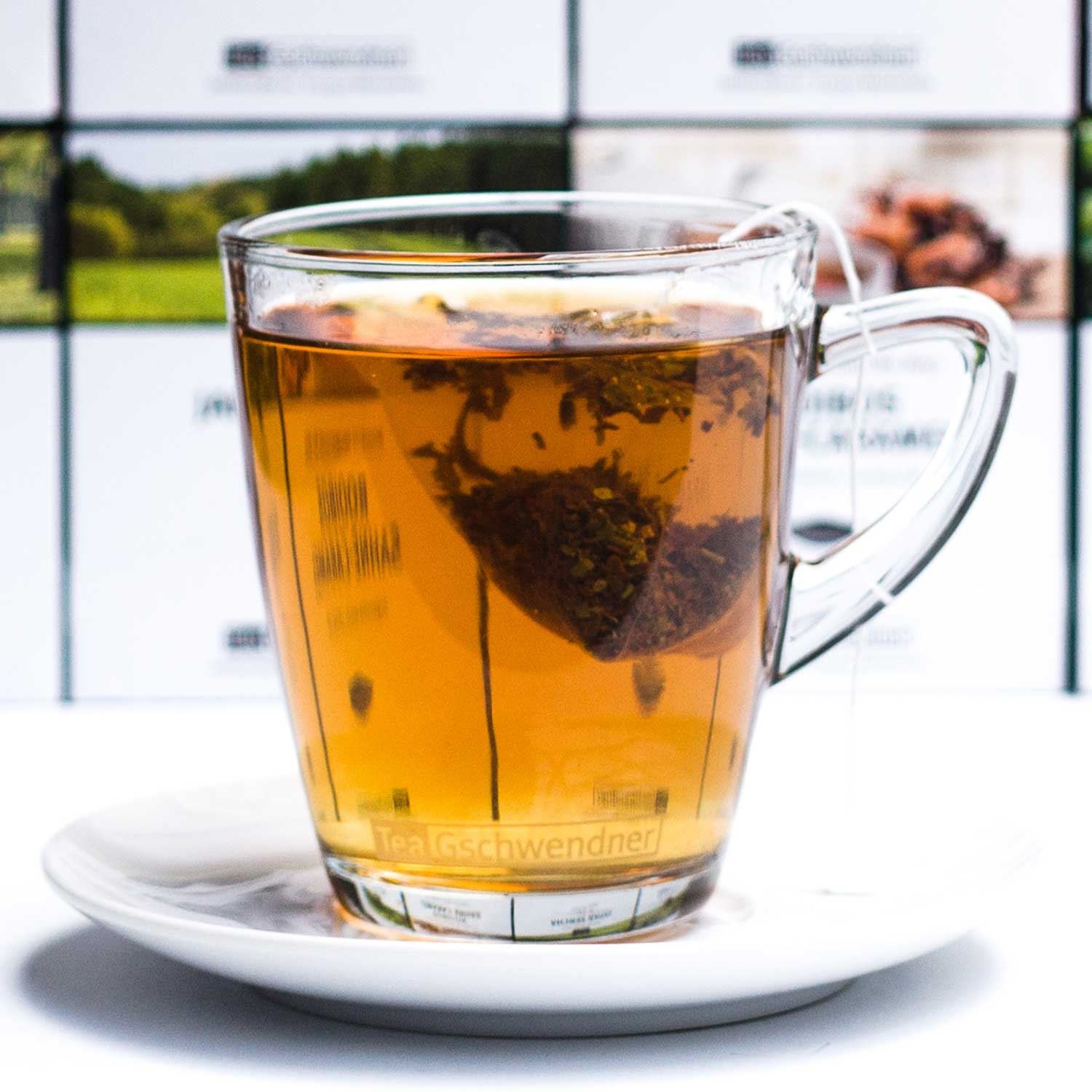 Transparentes Teeglas mit Teebeutel auf Untertasse, tee, tee-aufguss, kräutertee, glasbecher, heißgetränk