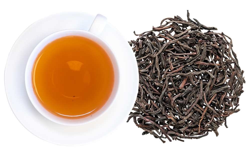 Weiße Tasse mit schwarzem Tee neben losen Teeblättern, Tee, Schwarztee, Blatttee, Teeblätter, Kanne