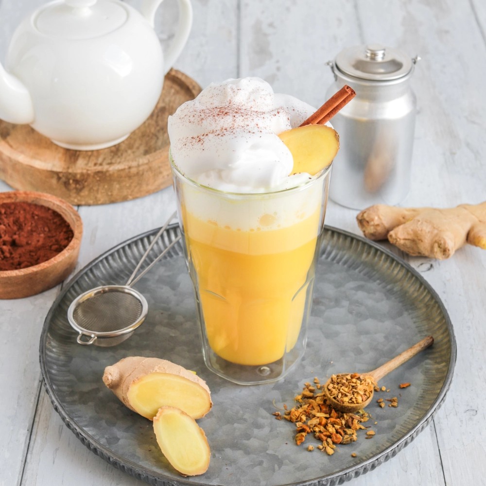 Glass of turmeric ginger latte with foam and cinnamon