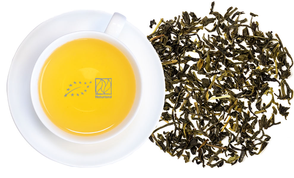 Weiße Tasse mit aufgebrühtem grünem Tee und Teeblättern