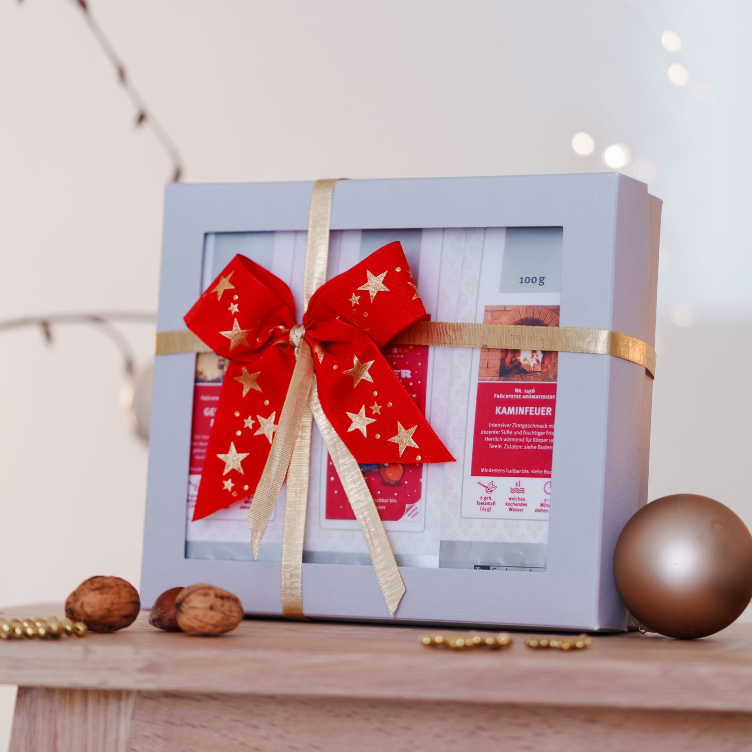 Geschenkbox mit Tees und roter Schleife auf Holztisch