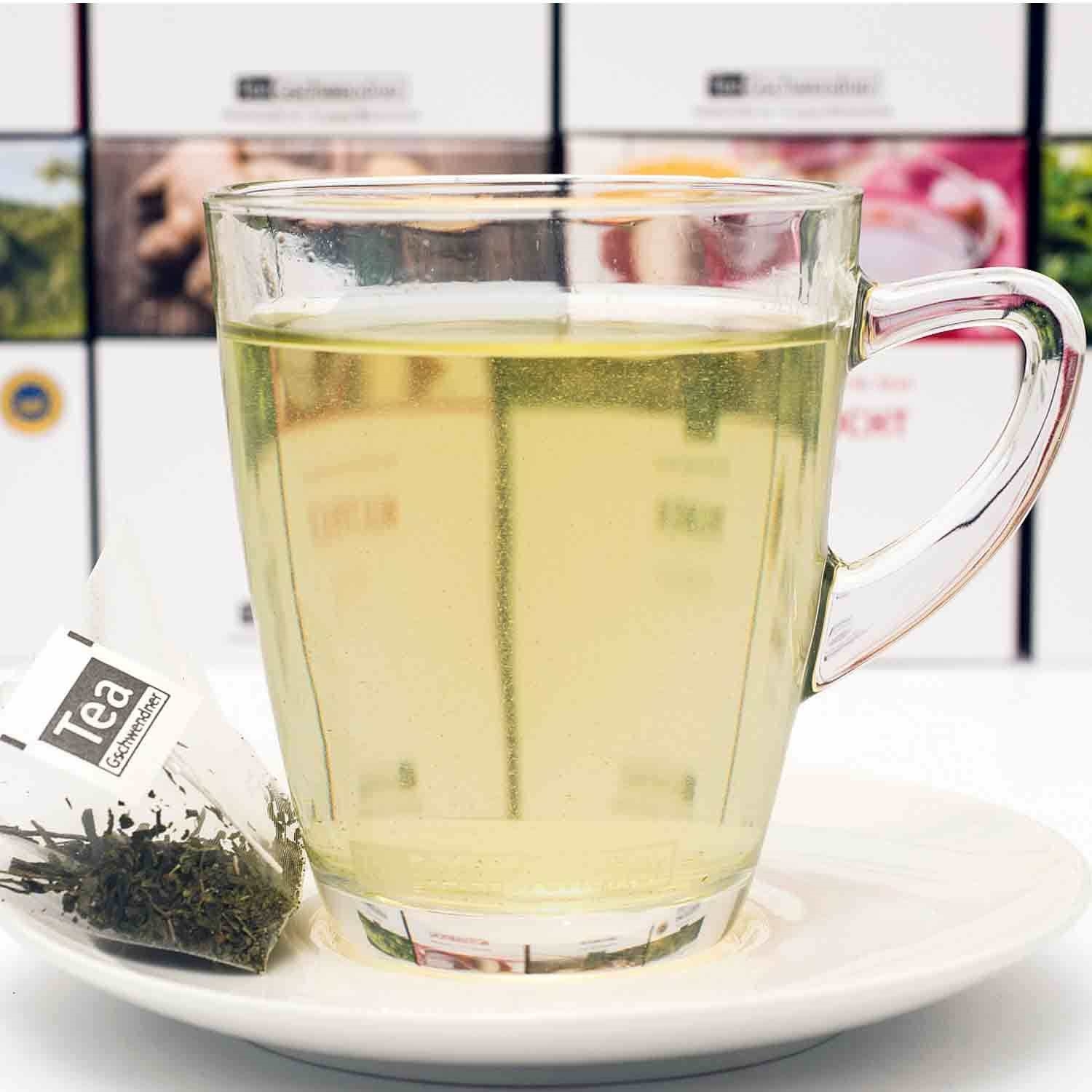 Heißer grüner Tee im Glas mit Teebeutel auf Teller, tee, glasbecher, zitronentee, kraeutertee, tee-beutel