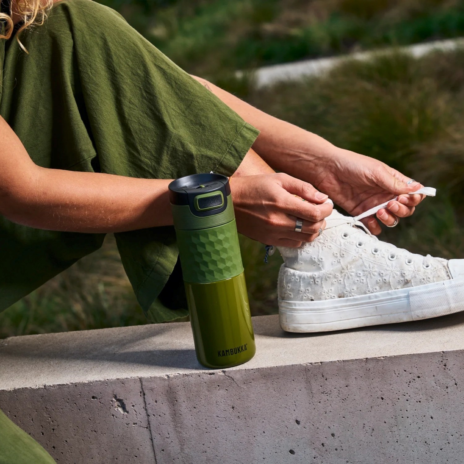 Grüne Kambukka Trinkflasche neben Sportschuh draußen, Grüner Becher, Trinkflasche, Sportflasche, Sneaker Reinigung/Schuhpflegemittel?, Löcher?
