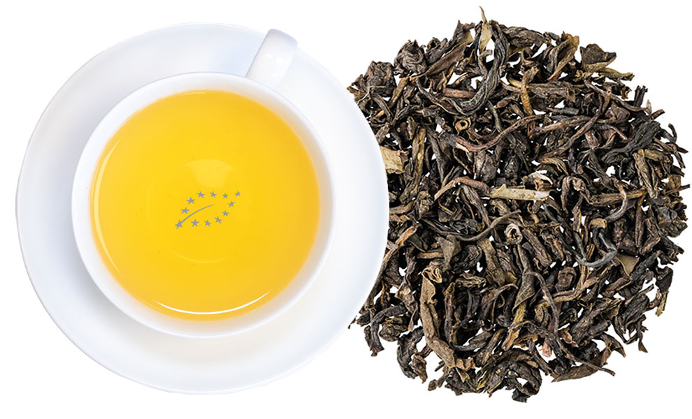 Weiße Tasse grüner Tee neben losen Teeblättern