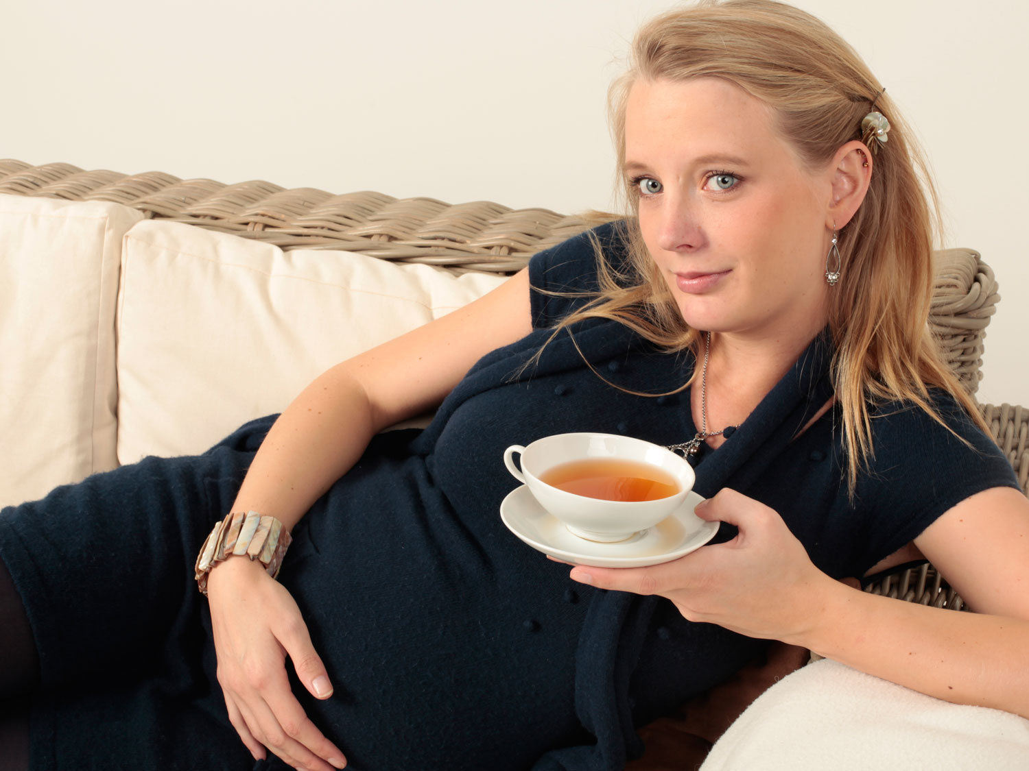 Schwangere Frau liegt entspannt auf dem Sofa und hält eine T, Tee, Teegetränk, Tasse, Frau, Halskette