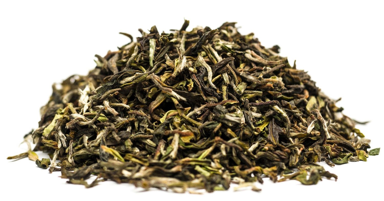 Haufen loser grüner Teeblätter in Nahaufnahme auf weißem Hintergrund