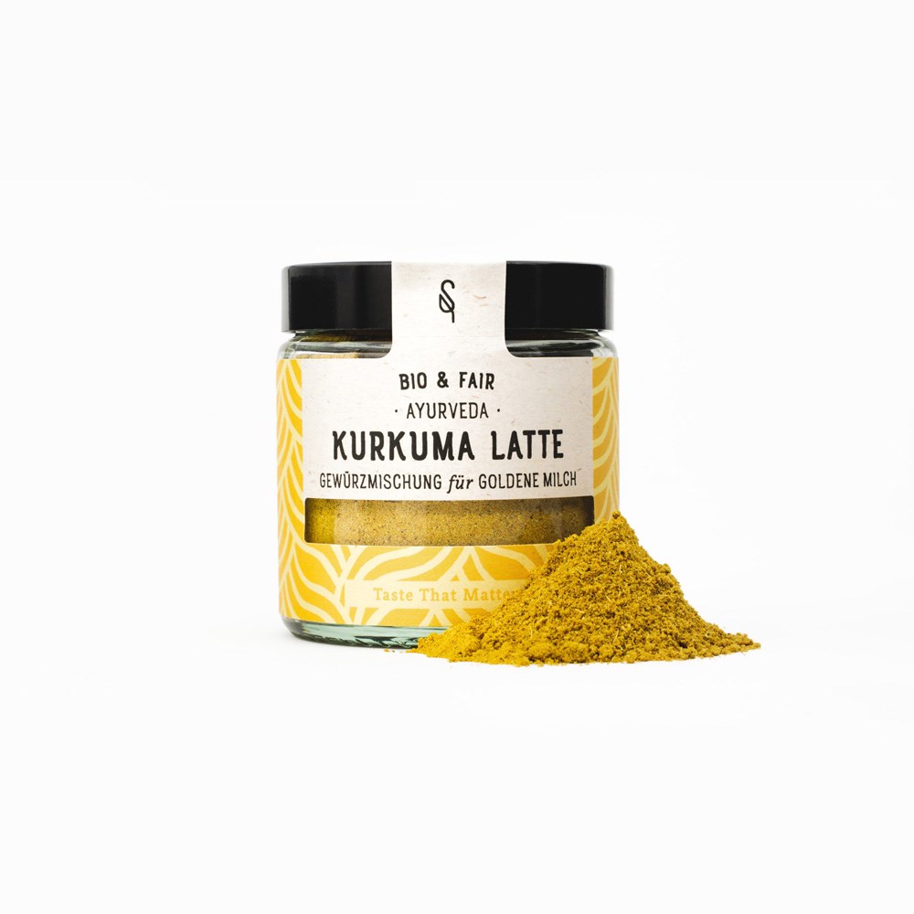 Bocal en verre de mélange d’épices ayurvéda curcuma latte bio pour lait doré avec tas de poudre devant