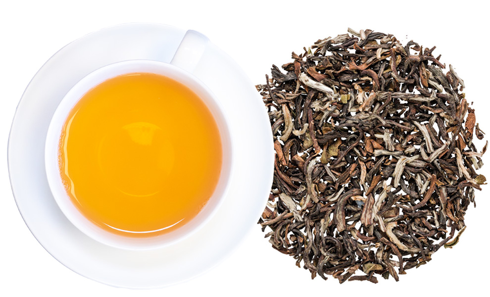 Weiße Tasse mit aufgebrühtem losem Tee daneben