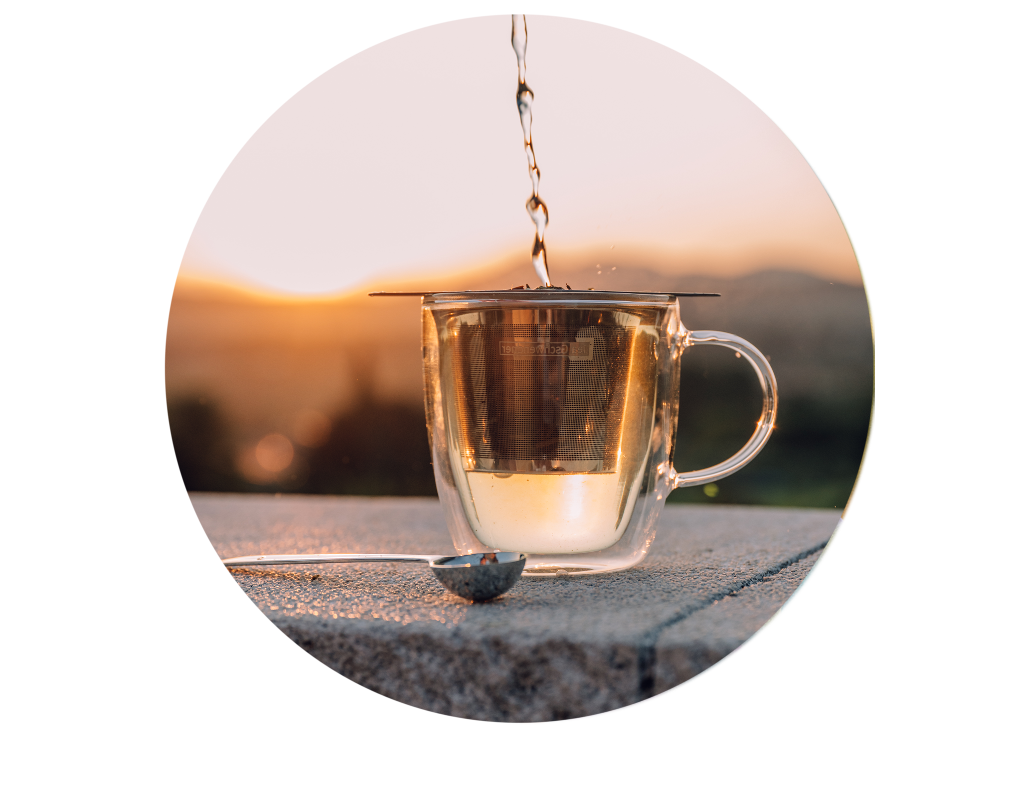 Heißes Wasser wird in Glasteetasse mit Teesieb gegossen