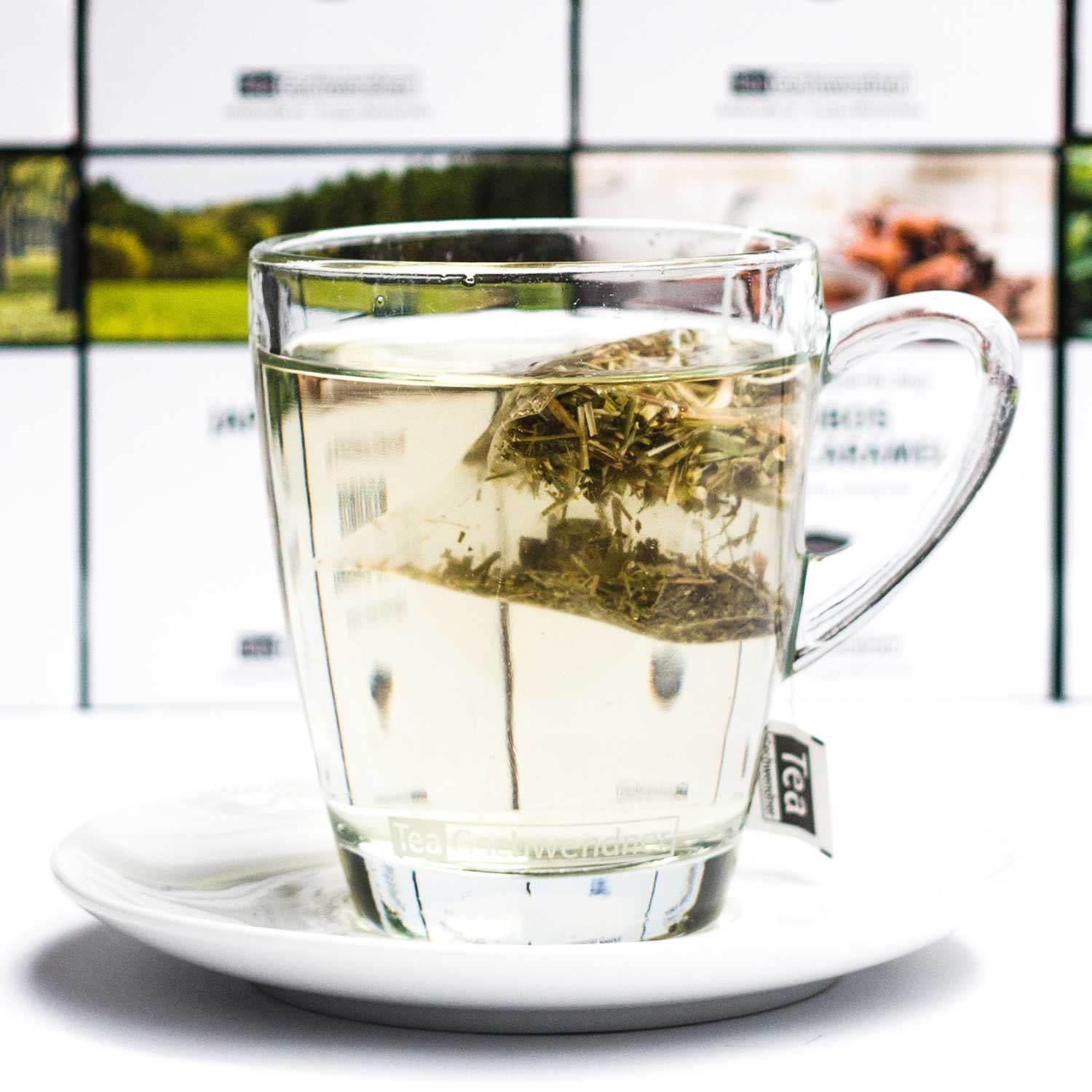 Heißer Kräutertee im Glas mit Teebeutel auf Teller, Teetraum, Kaffeetee, Glasbecher, Teebeutel, Glas