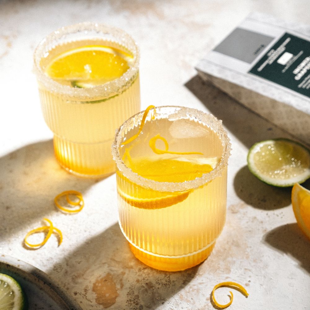 Two lemon orange drinks in ribbed glasses with sugar rim