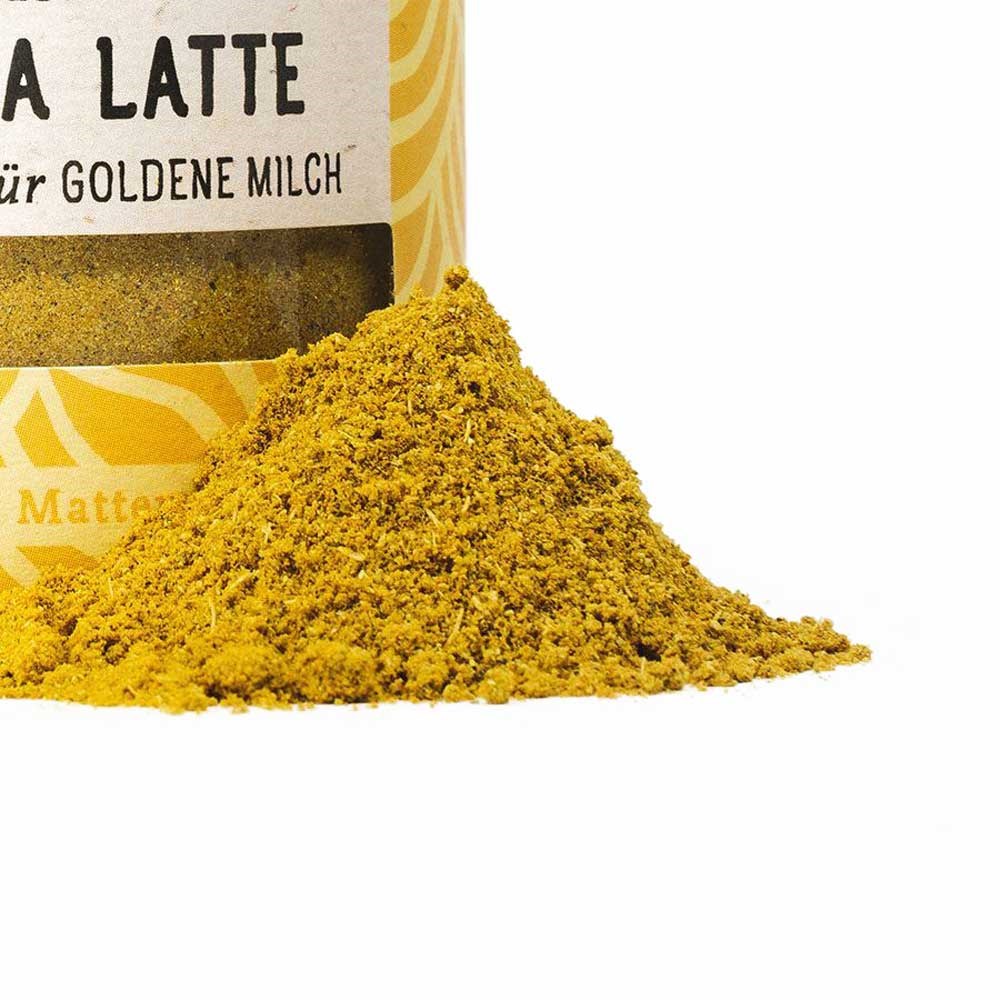 Poudre jaune de curcuma latte, mélange d’épices pour préparer un lait doré devant une boîte