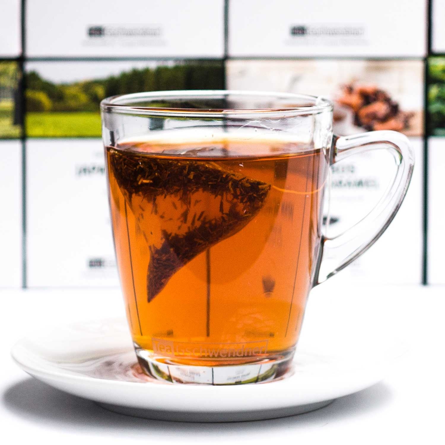 Heißer Tee im Glas mit Teebeutel auf Untertasse, Teeglas, Teeblatt, Klarglas, Teebeutel, Kaffeetasse
