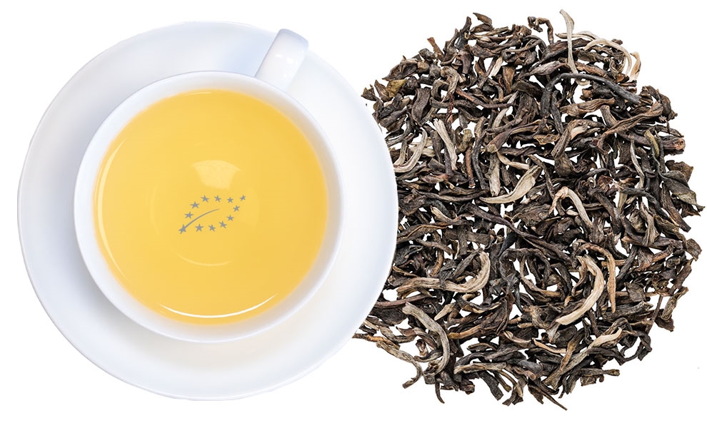Weiße Tasse mit gelbem Tee und losen Teeblättern