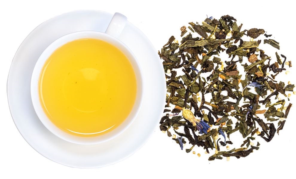 Weiße Tasse mit aufgebrühtem Grüntee und losen Blättern, tee, tee mit blüten, honiggelb tee, loser tee, frühstückstee