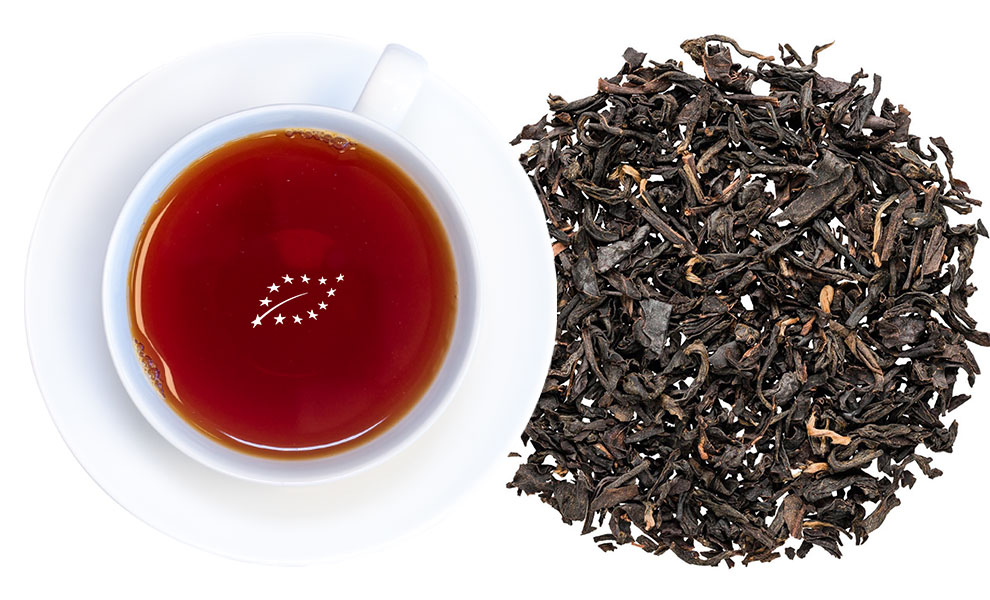 Weiße Tasse mit Schwarzem Tee und losen Teeblättern