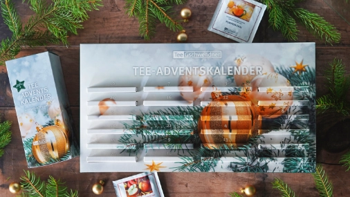 Tee-Adventskalender auf einem Holztisch, dekortiert mit Tannenzweigen