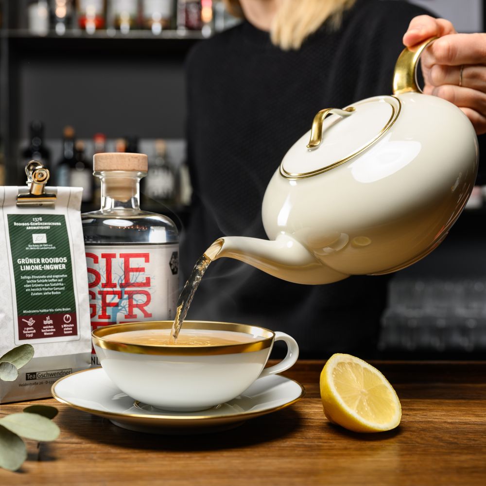 Teapot pouring green rooibos lemon ginger into cup
