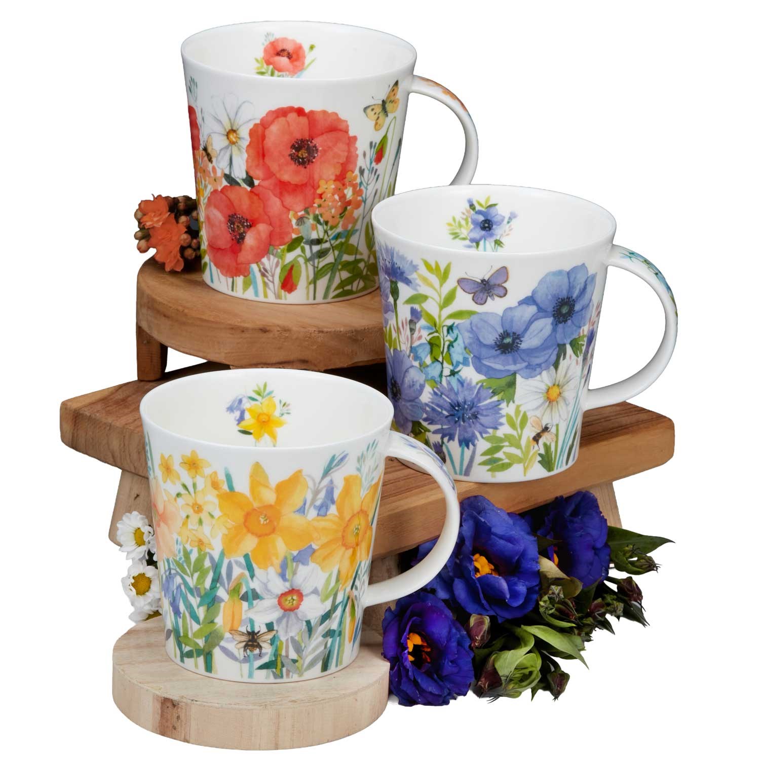 Drei Porzellanbecher mit farbenfrohen Blumenmustern, arrangiert auf Holzpodesten, ideal für Kaffee oder Tee, Tassen, Kaffeetassen, Porzellan, Blumenmuster, Tassen-Set