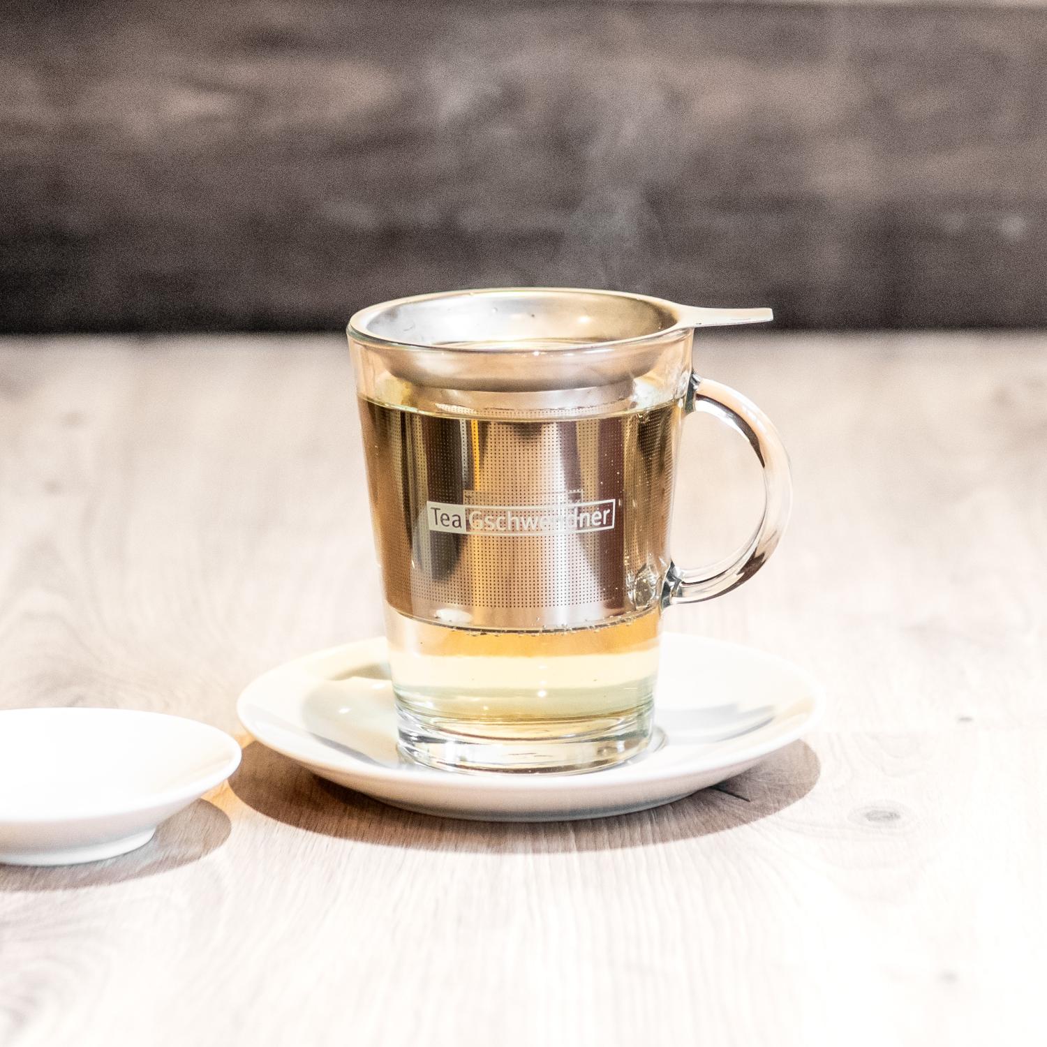 Heißer Tee im Glas mit Edelstahl-Teefilter
