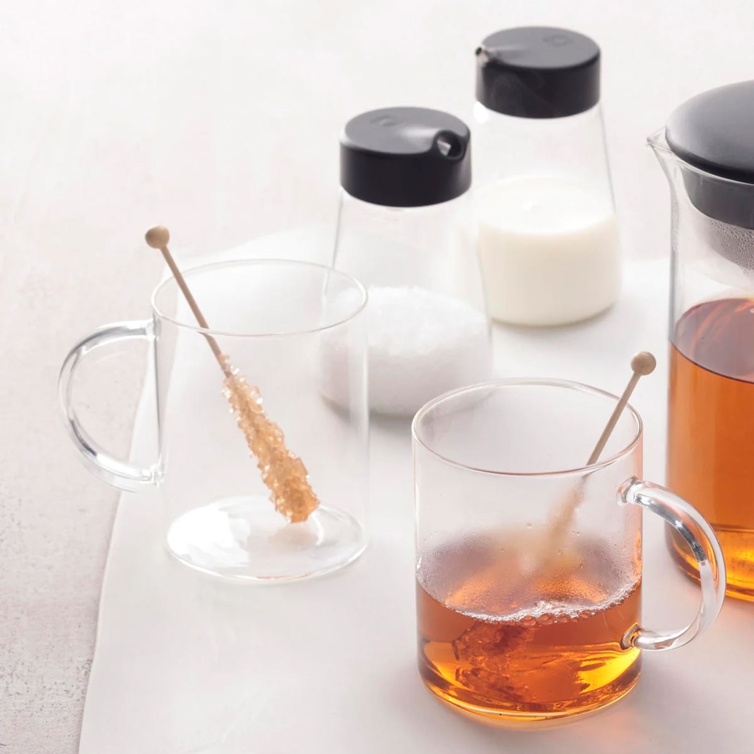 Transparente Teegläser mit Kandiszucker und Zubehör, Stövchen?, Getränk, Glas, Löffel, Zucker, Milch, Kaffee, Becher, Teekanne, Honig