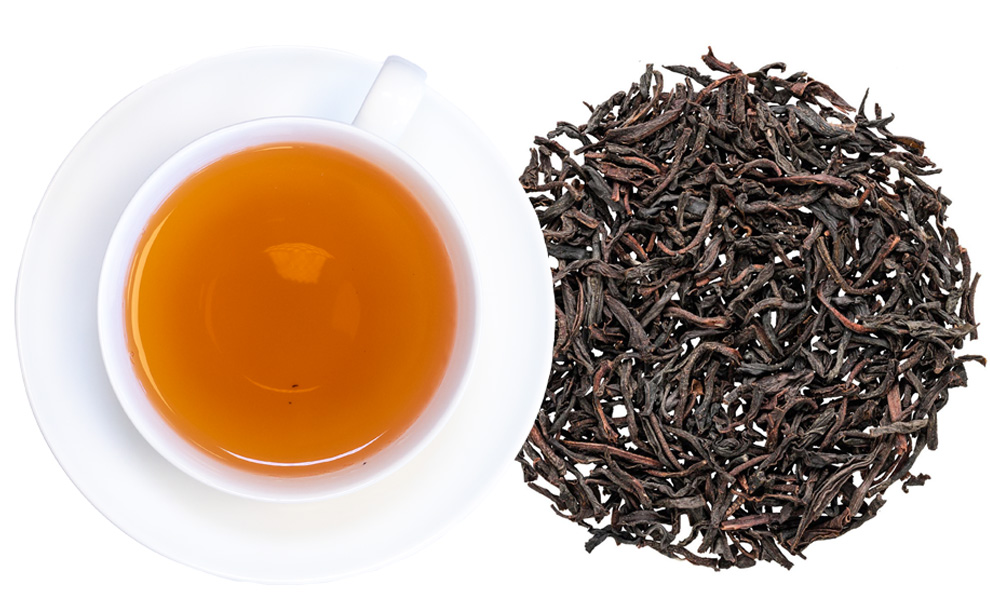 Tasse aufgegossener schwarzer Tee mit losen Blättern