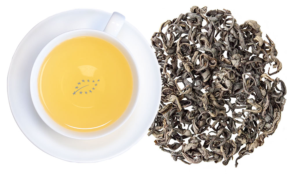 Tasse grüner Tee neben losen Teeblättern
