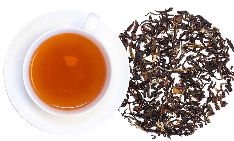 Weiße Tasse Schwarztee neben losen Teeblättern, Tee, Schwarztee, Teeblätter, Tasse, Kolloquium Teekreis